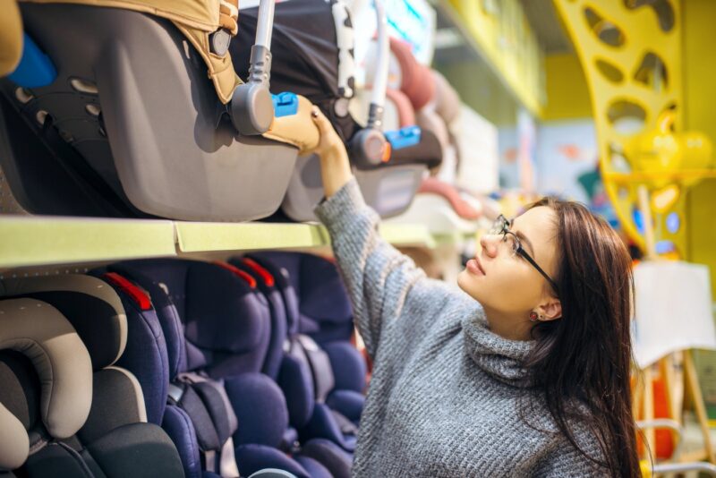 Pregnant mom-to-be looking at car seats at a store