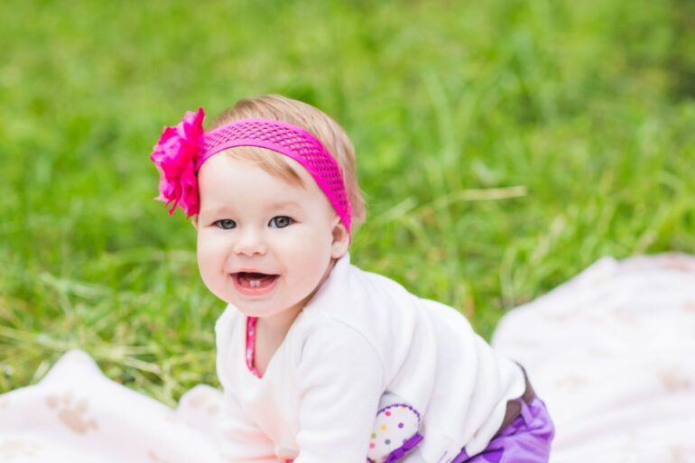 Baby with pink bow on the grass - Swedish girl names